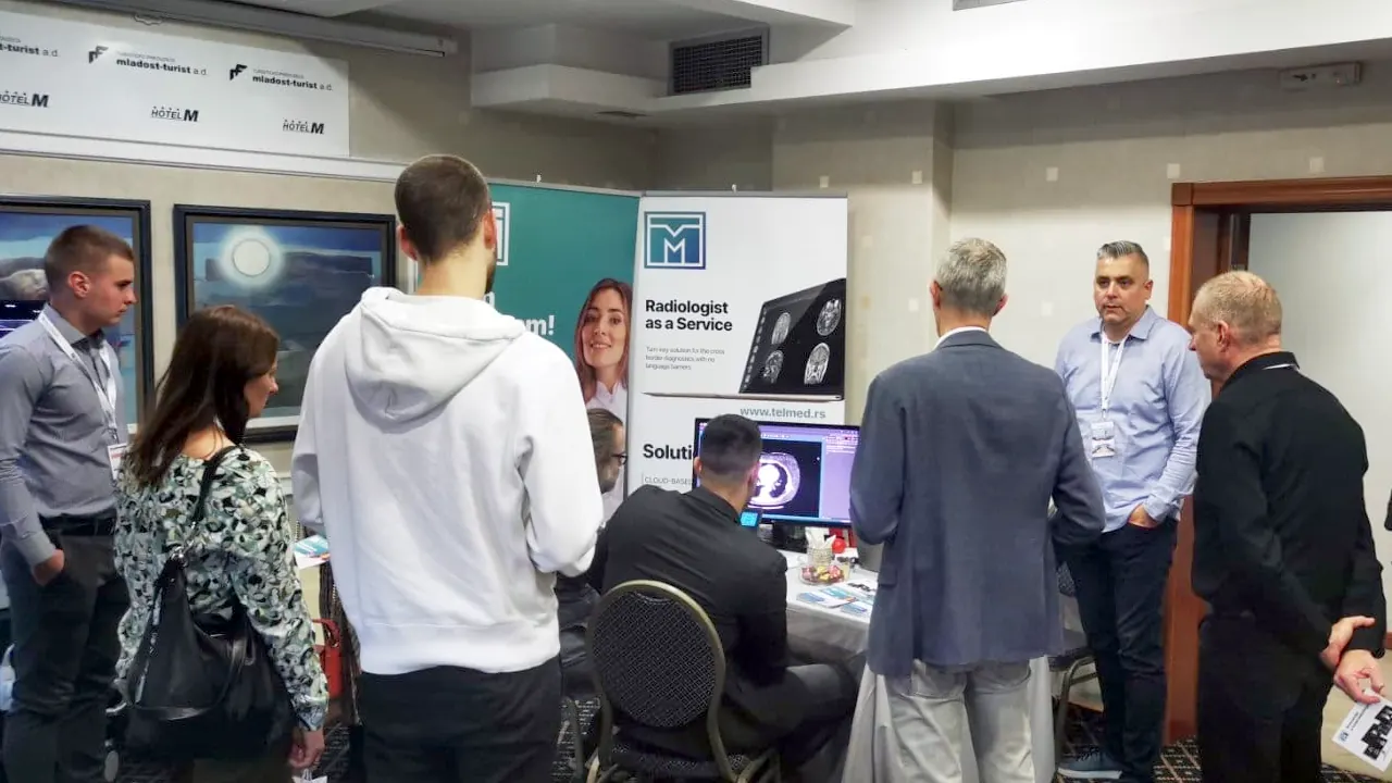 Visitors at the Telmed stand with a CT image on screen